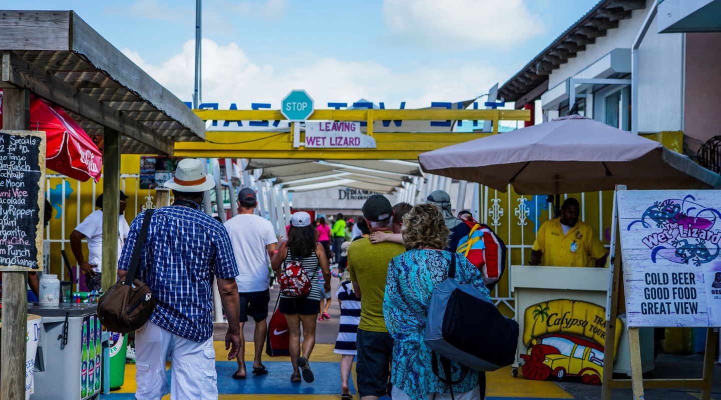 Group of tourist walking down a pier, surrounded by colorful stores and decorations. 