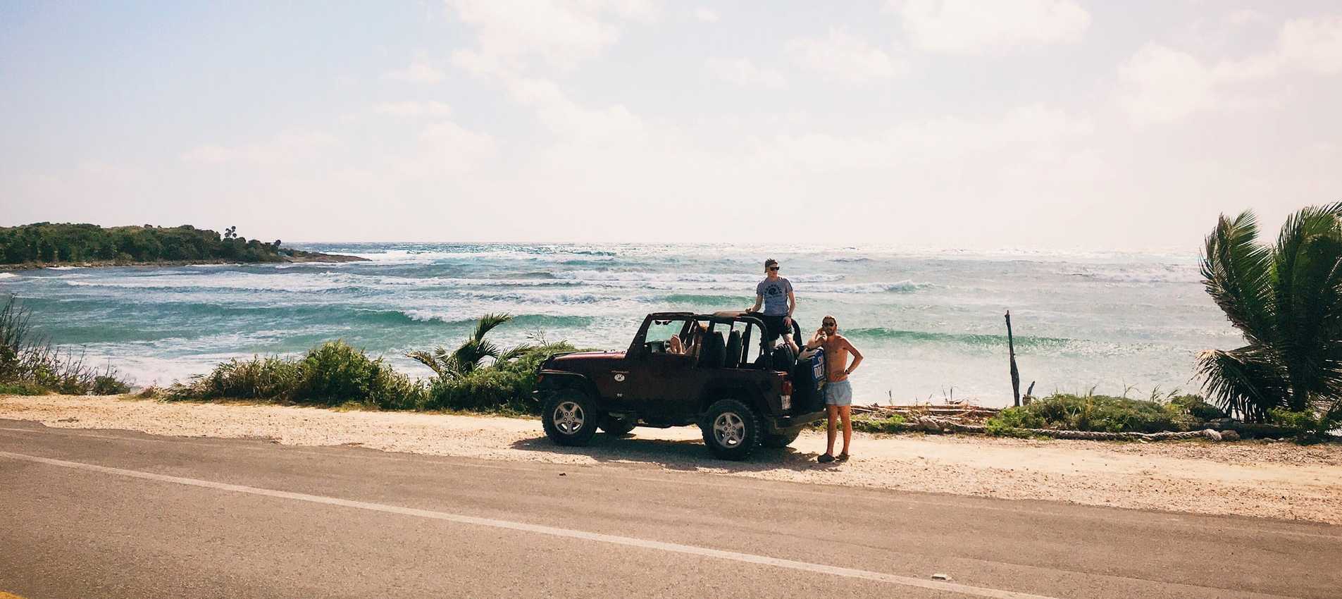 people on jeep with ocean in backdrop