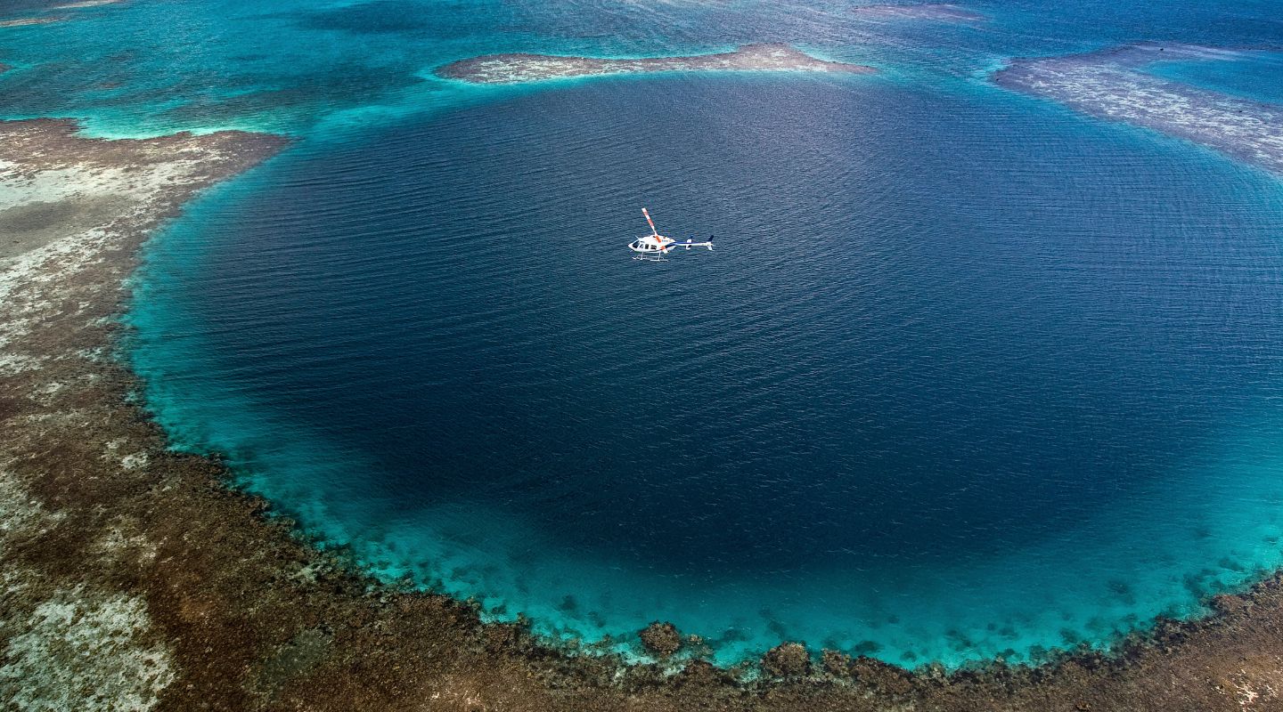 Aereal view of the blue hole, a large hole in the ocean with a boat sailing through it
