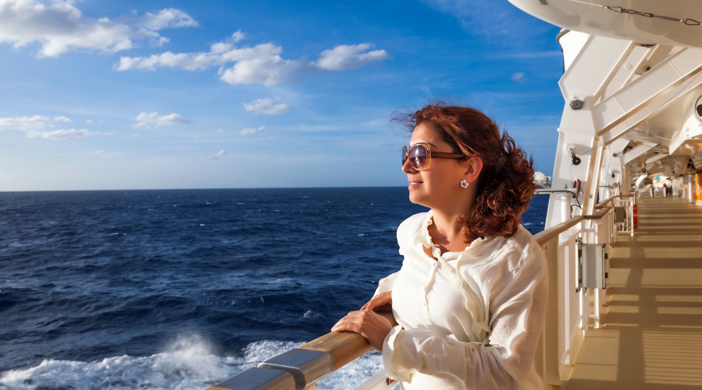 Cruise ship passenger looking at the ocean leaning on a rail. 