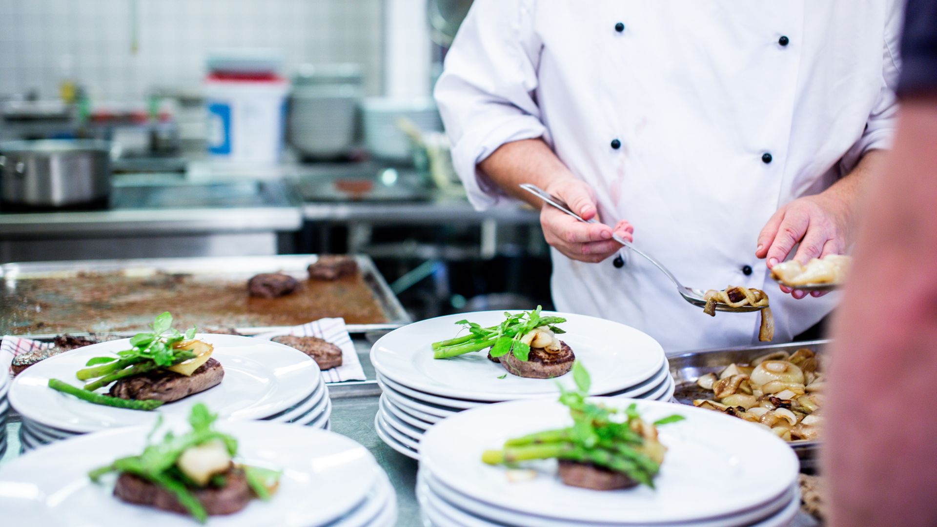 Food being plated by a chef inside a kitchen