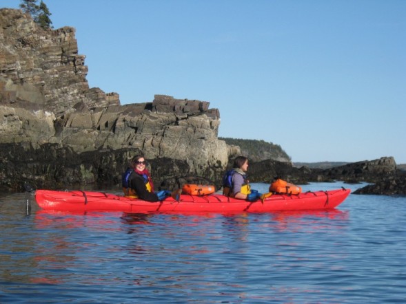 Kayaking past exposed layers of sea cliff rock millions of years old