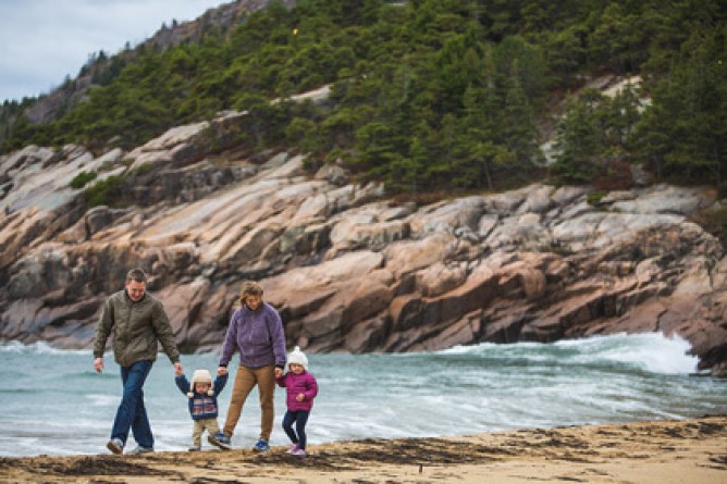 Family walking by the water on rocky shoreline