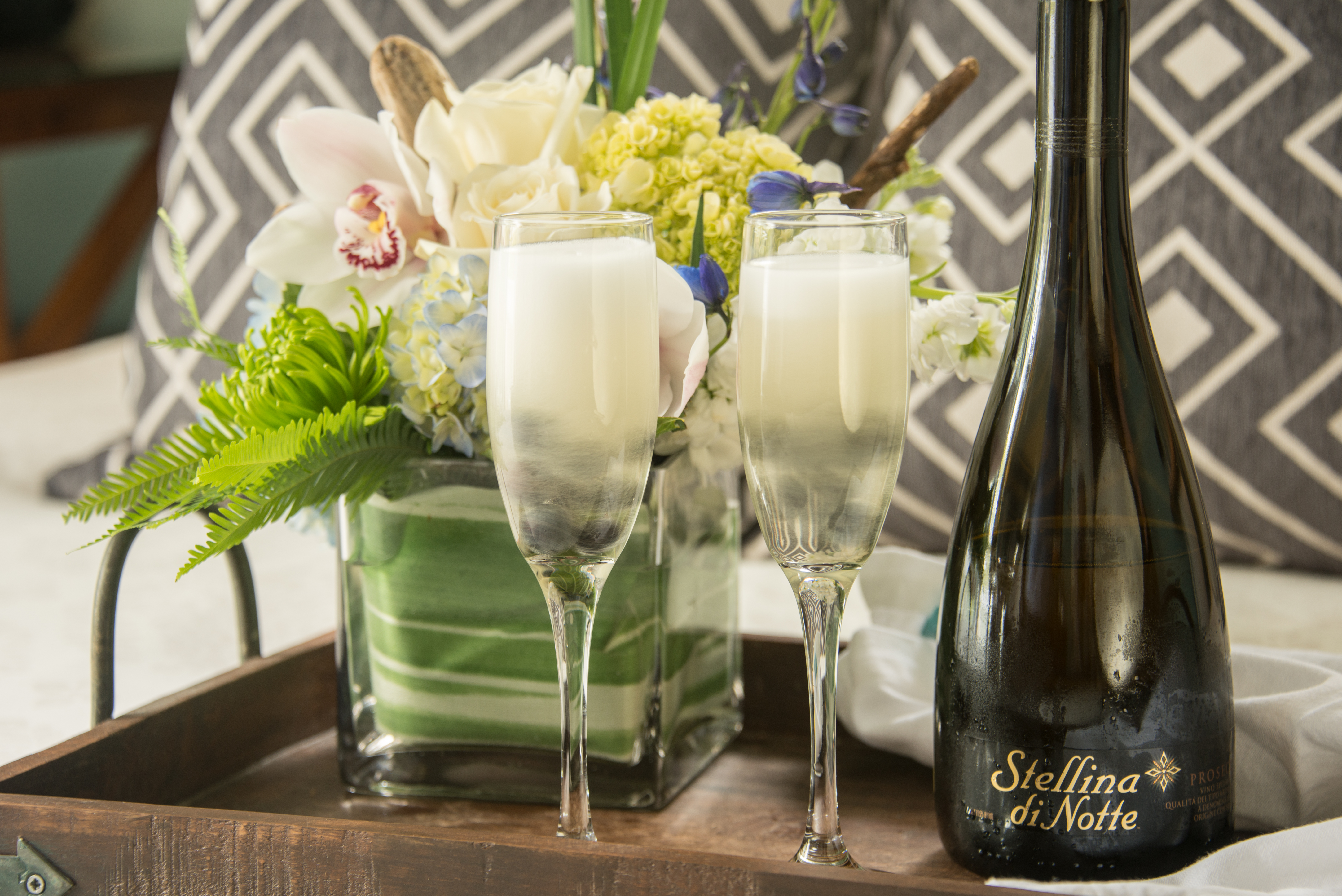 Two longstem glasses next to a bottle of of Stellia di Notte Prosecco