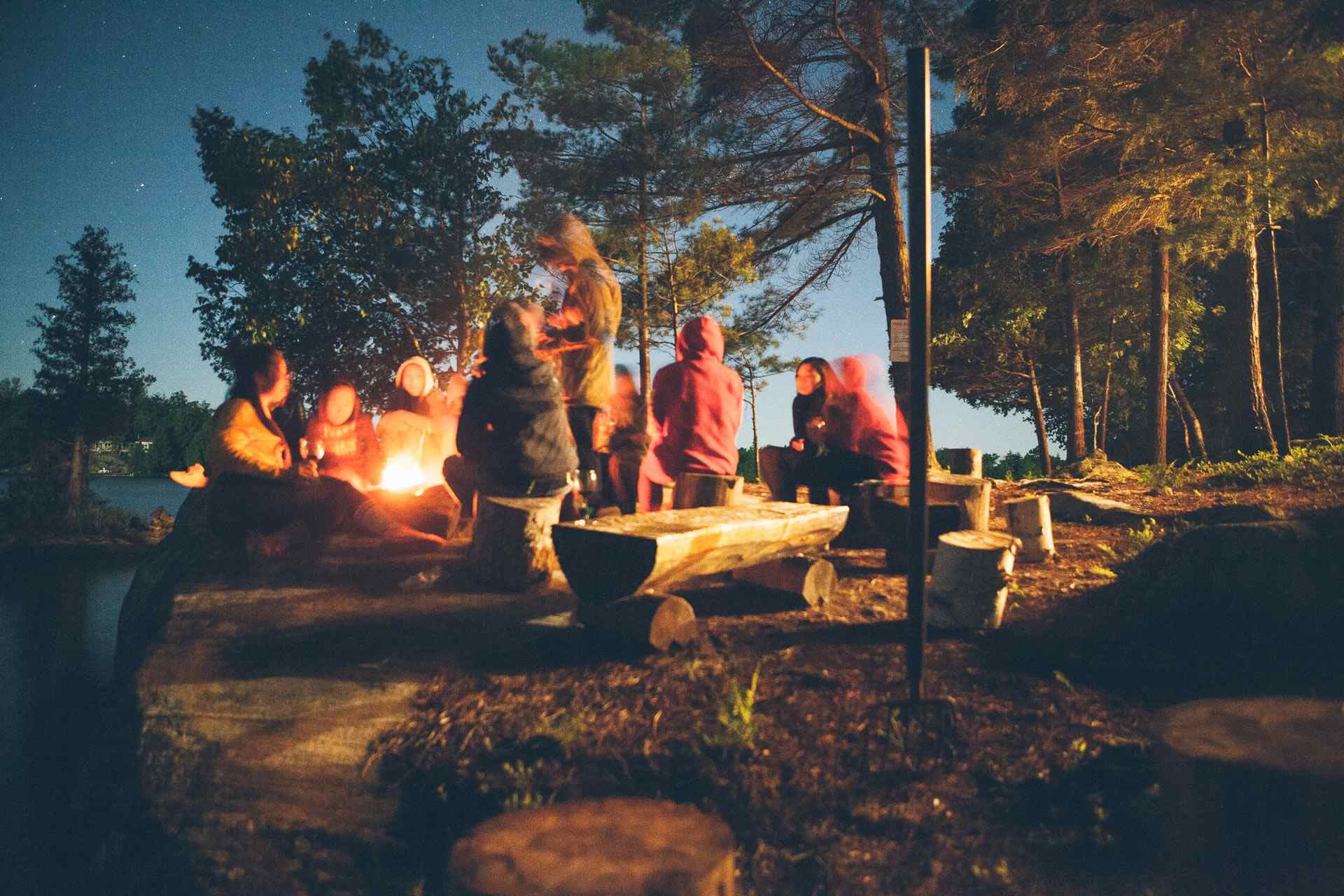people and campfire by side of lake