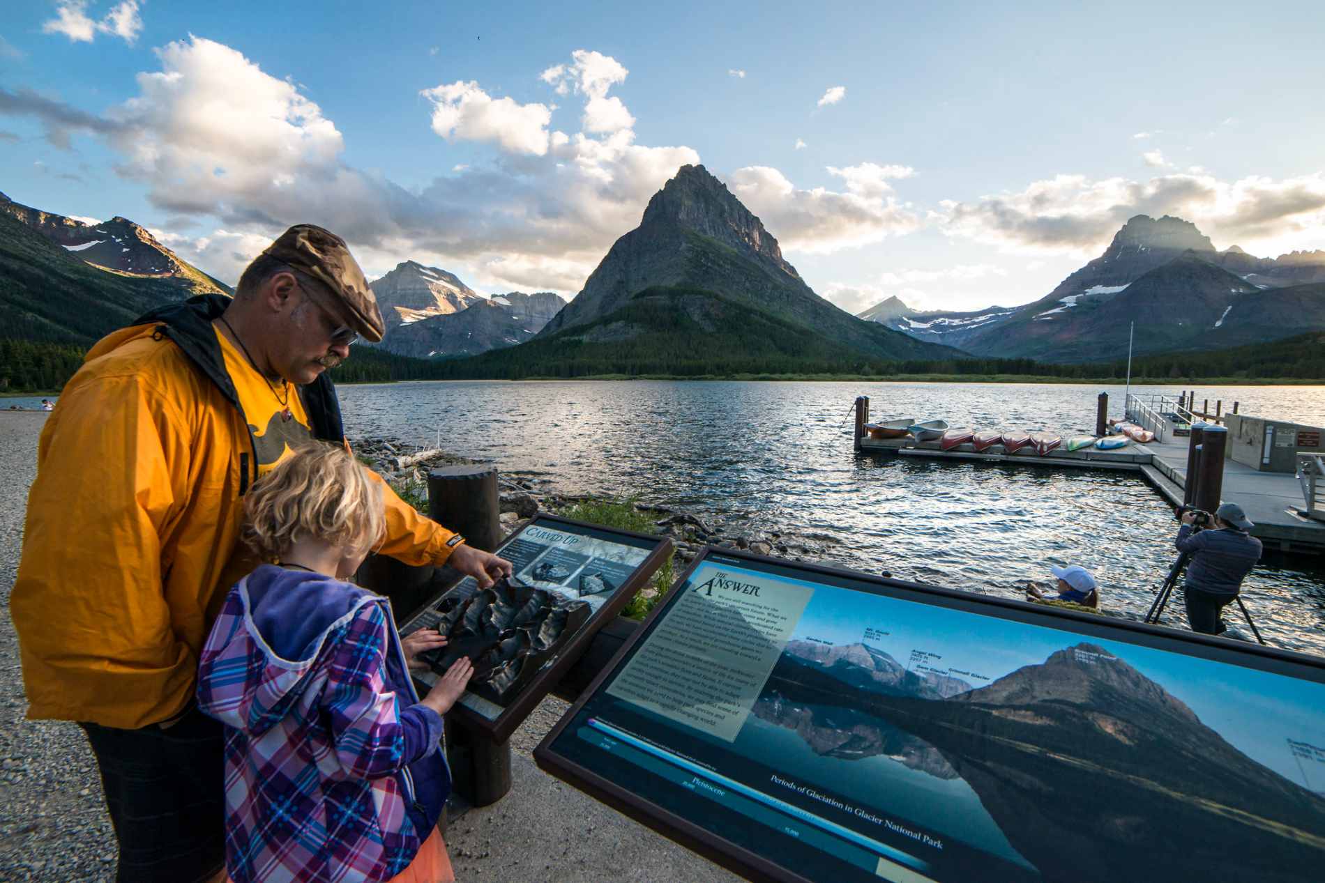 A family reading an informational sign in Glacier National Park