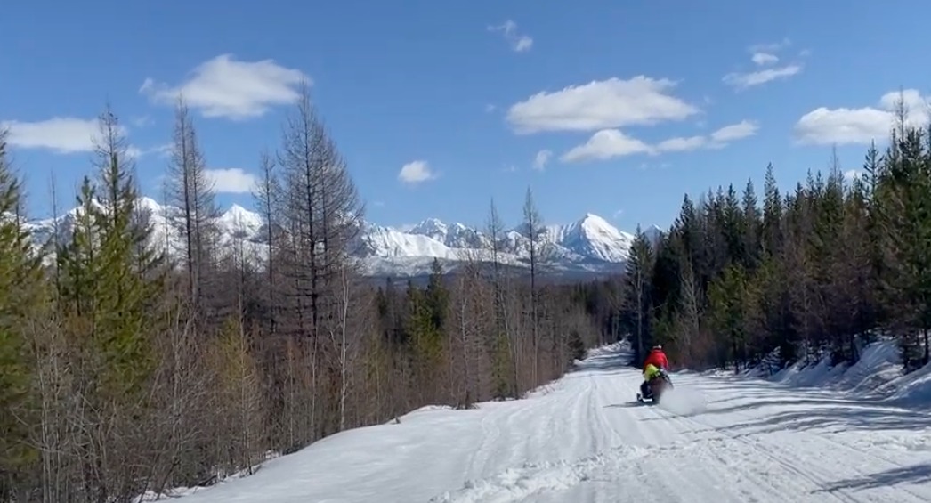 man riding snowmobile outside of Glacier National park