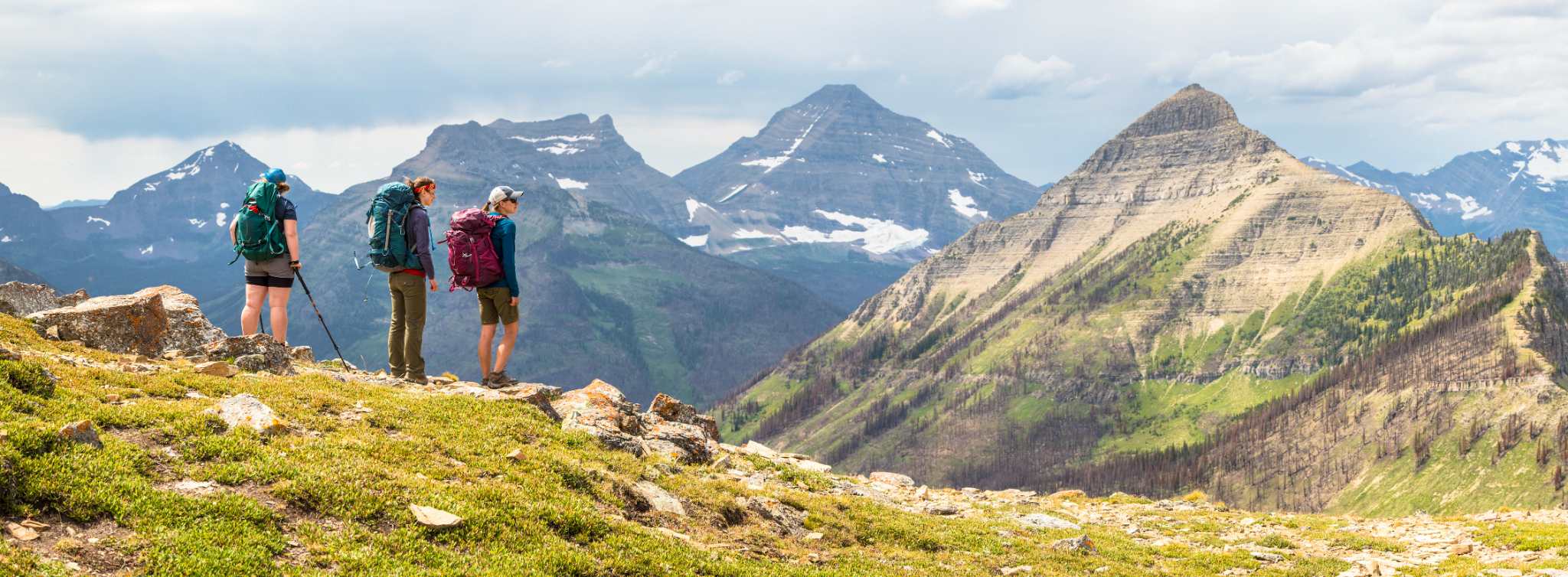 several women hiking in Glacier Park on mountain pass