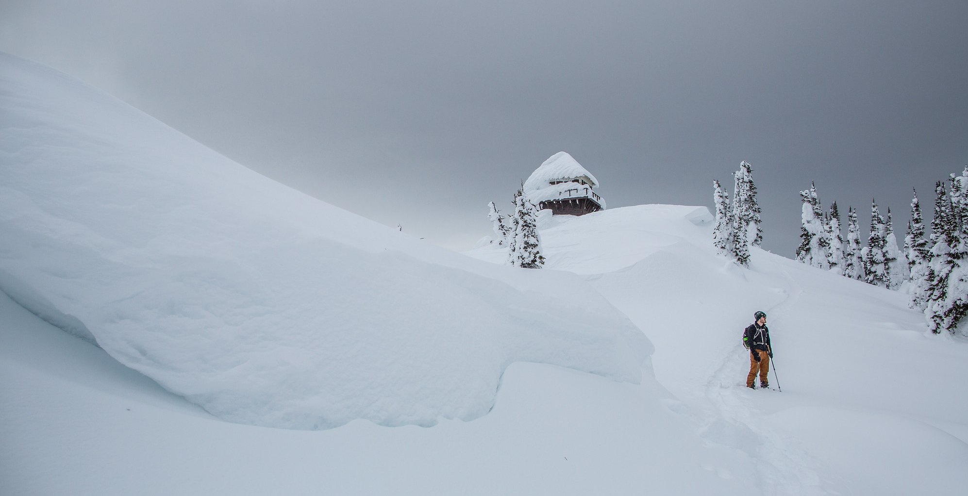 man hiking up to winter lookout in deep powder snow